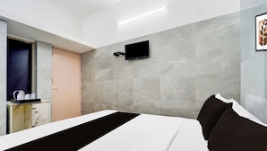 Quarto de hotel com uma cama, televisão de tela plana fixada na parede e detalhe de parede em marmore.