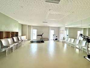A spacious room with a treadmill, exercise bike, and seating area. - APPART ONE ERAGNY (Éragny)