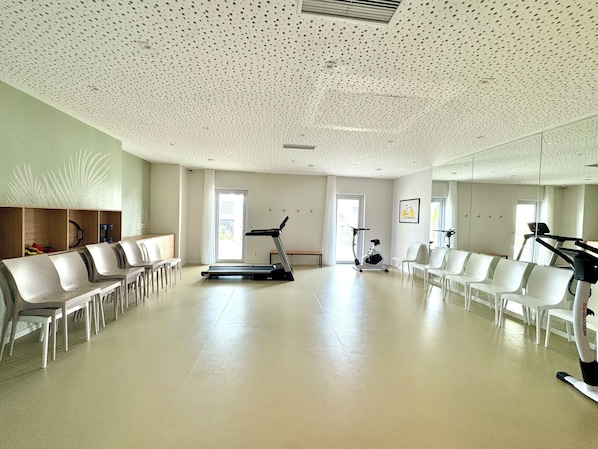 A spacious room with a treadmill, exercise bike, and seating area.