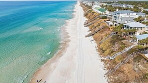 Una propiedad costera con acceso directo a la playa, un paseo marítimo de madera y varias edificaciones.