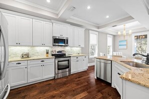 A modern kitchen with white cabinets, stainless steel appliances, and a granite countertop.