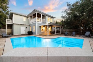 Una casa de dos pisos con piscina, un patio cubierto y un patio trasero cercado.