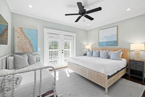A bedroom with a bed, bedside tables, a ceiling fan, and artwork on the walls.