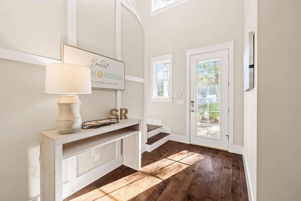 A hallway with a white console table, a framed sign, and a door leading outside.