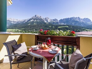 A balcony with a table set for two, overlooking a mountainous landscape. - Apparthotel Tom Sojer (Tirol)