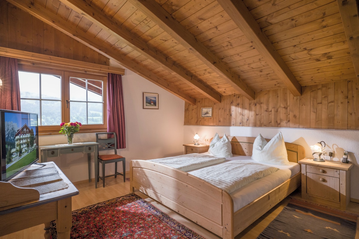 A wooden room with a bed, a desk, and a window.