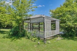A wooden gazebo with a lattice roof structure, surrounded by lush greenery and a clear blue sky. - Spacious Creekside Suite Near Chicago (barrington hill)