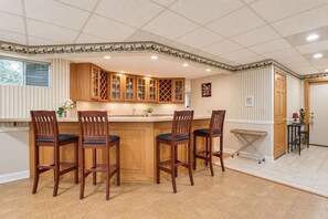 A kitchen with wooden cabinets, a bar area with stools, and a tiled floor. - Spacious Creekside Suite Near Chicago (barrington hill)