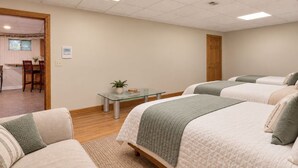 Habitación de hotel con cama, sofá, una mesita con una planta y vista al comedor.