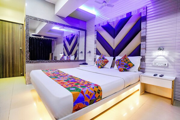 Una habitación de hotel moderna con una cama grande, una mesita de noche, un espejo y una pared con diseños geométricos.