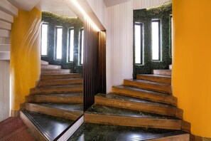A staircase with a wooden finish and a green wall at the top.