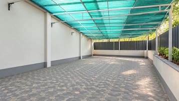 A covered patio area with a patterned floor and a green overhead structure.