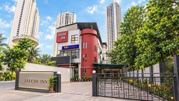 A hotel entrance with a gated driveway, a sign for 'Jayesh Inn,' and a 'Fab Hotels' sign.