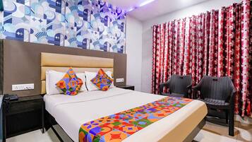 Habitación de hotel con cama, mesitas de noche, teléfono, cabecera, pared con estampado y ventana con cortinas.