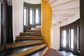 Una escalera con un diseño original, que presenta un pilar amarillo y una pared verde.