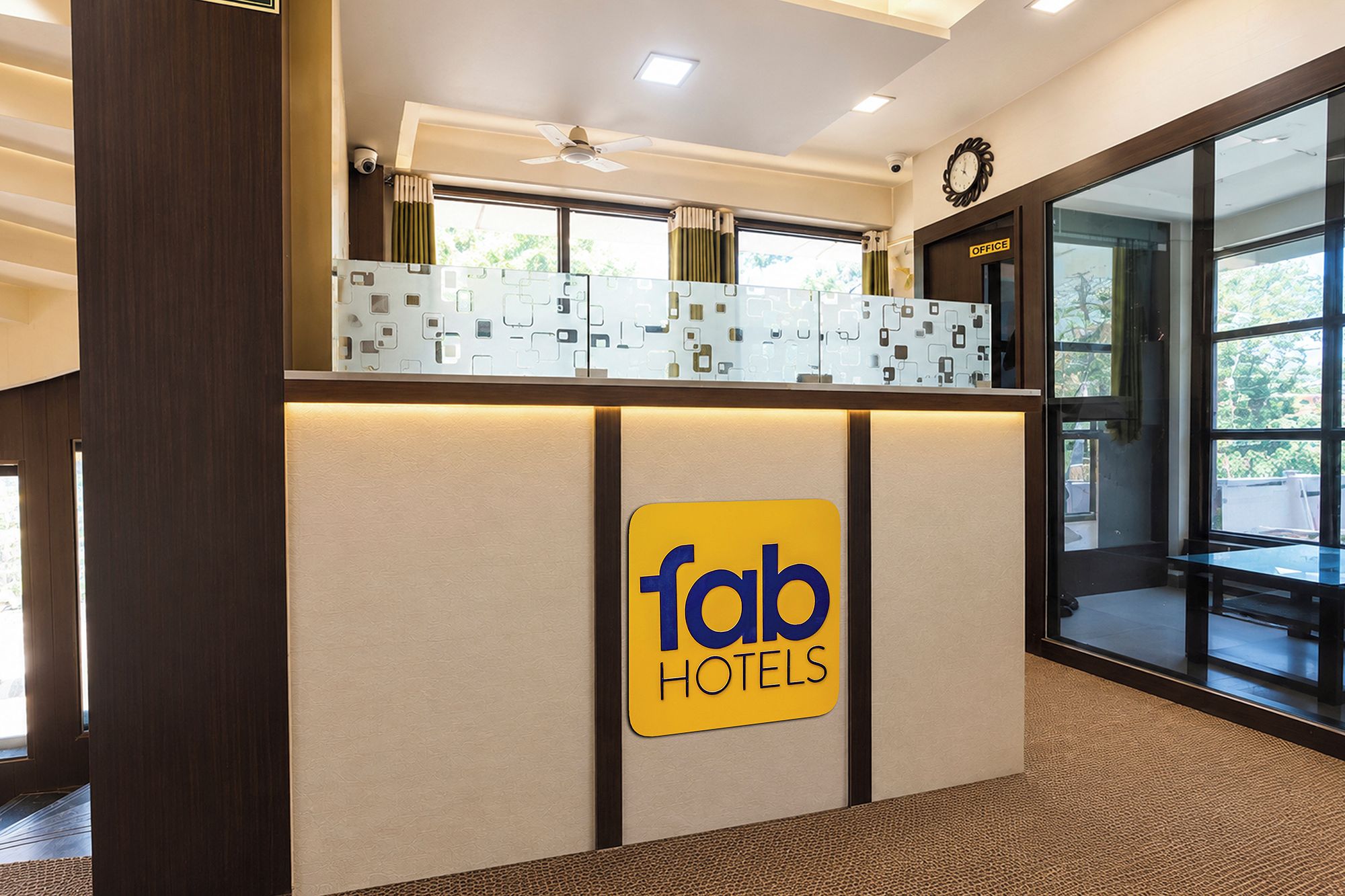A reception desk with a sign for 'fab hotels' and a clock above it.
