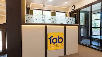 A reception desk with a sign for 'fab hotels' and a clock above it.
