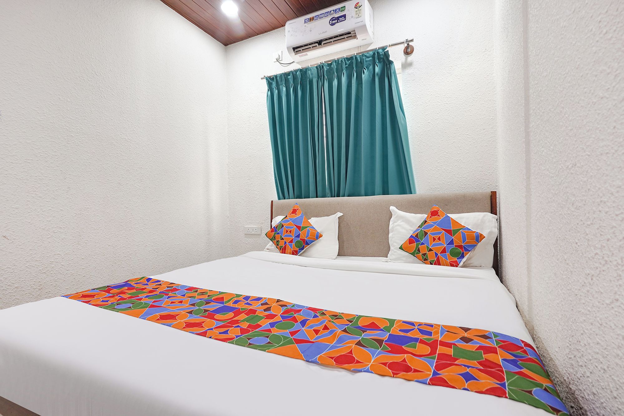 Una habitación de hotel con una cama, una ventana con cortinas y un equipo de aire acondicionado.