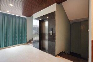 An elevator with a control panel, a staircase, and a view of the outside. - FabHotel Gayathri Comforts (Bangalore)