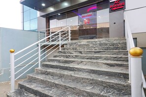 Una escalera de mármol con barandillas blancas que conduce a la entrada de un edificio.