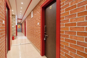 A corridor with red-framed doors, a fire extinguisher, and a number sign on the wall. - FabHotel Love Point (Barasat)