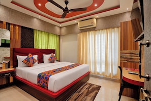 A modern hotel room with a large bed, a ceiling fan, an air conditioning unit, and a wooden desk with a chair. - FabHotel Love Point (Barasat)