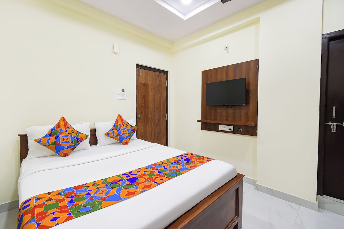 A hotel room with a bed, a TV mounted on the wall, and a door.