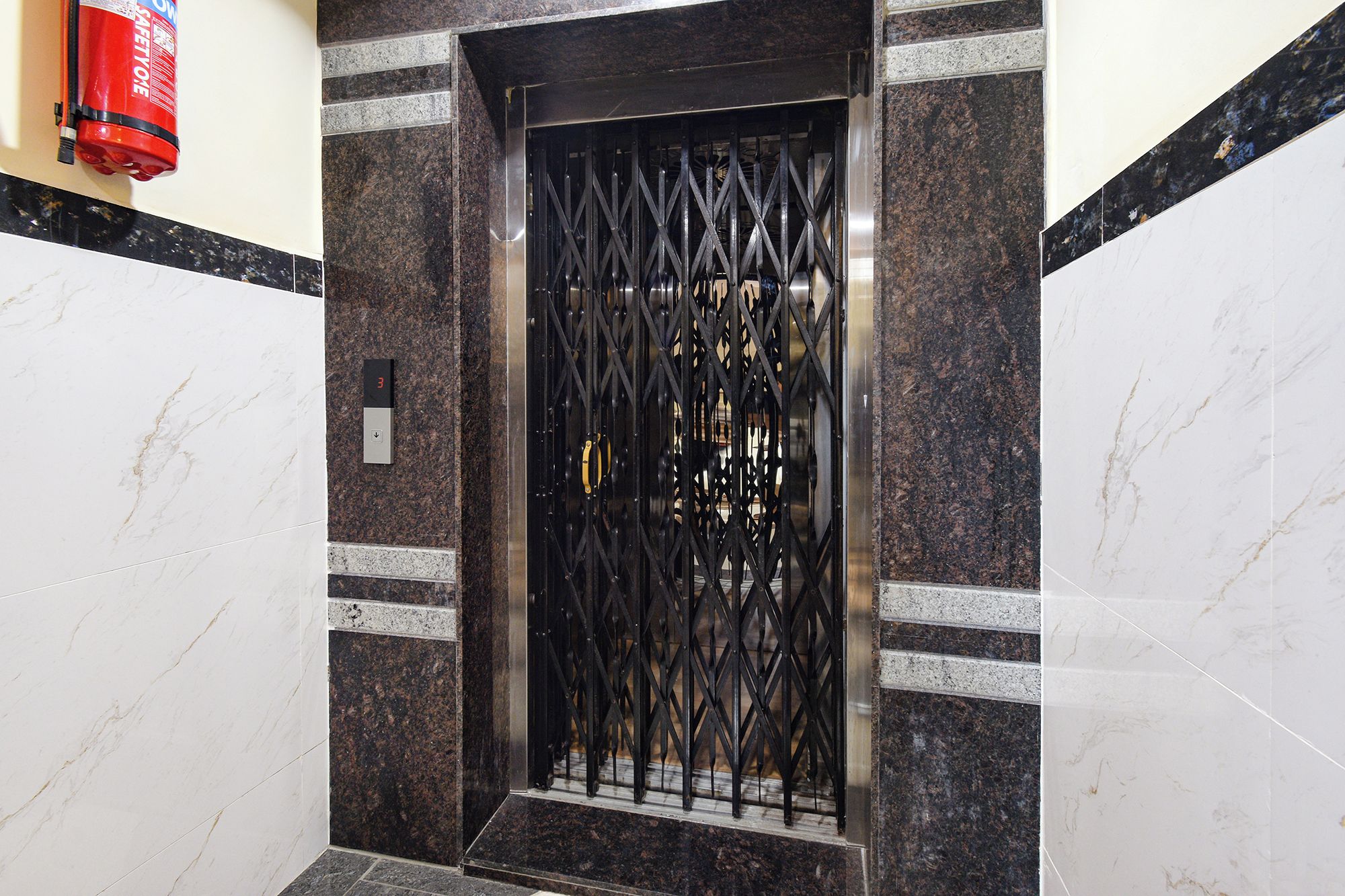 Una reja de metal negro con un candado de seguridad, un extintor y un indicador de piso.