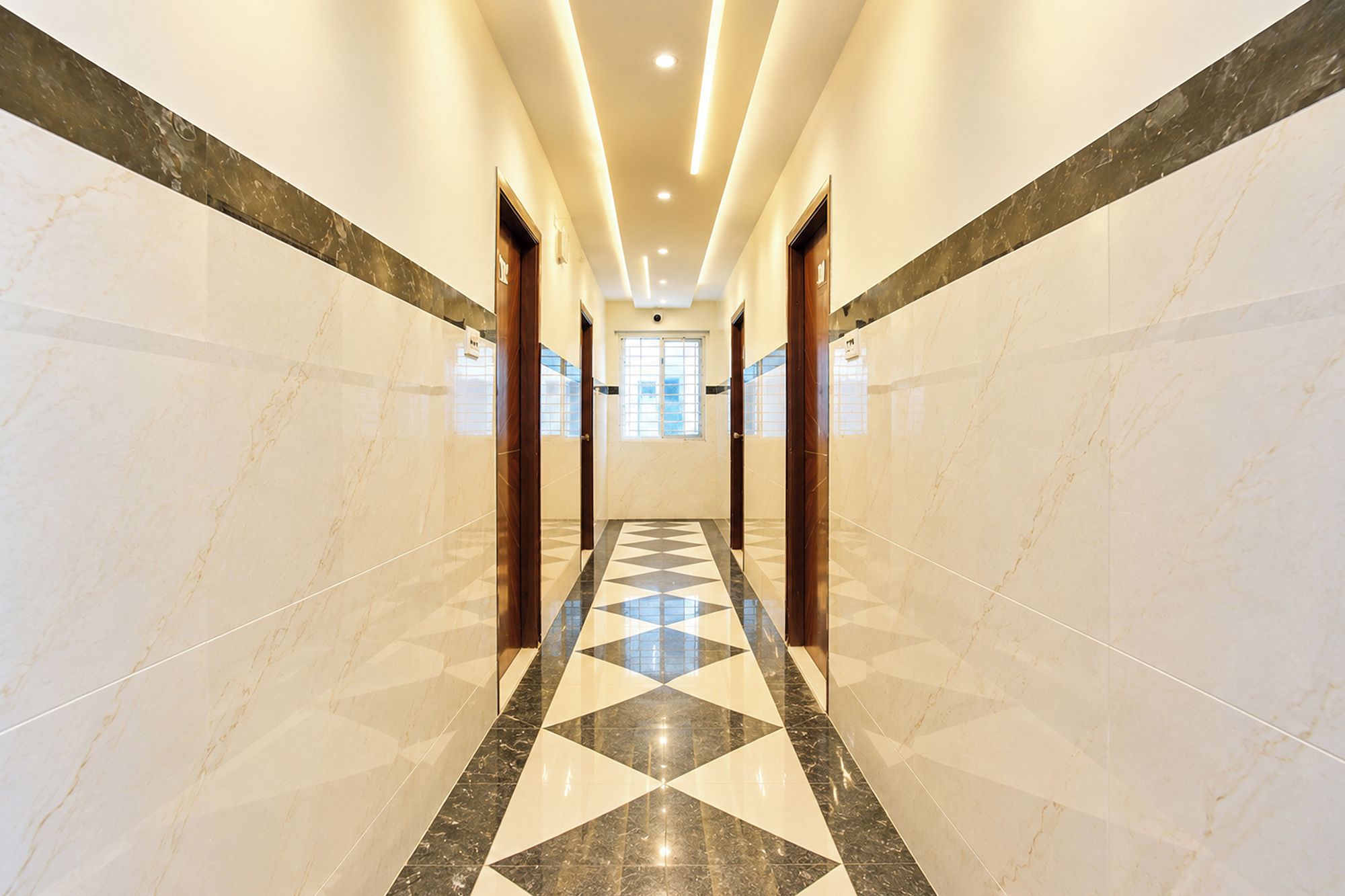Un pasillo de hotel con paredes de mármol y un suelo de diseño geométrico.