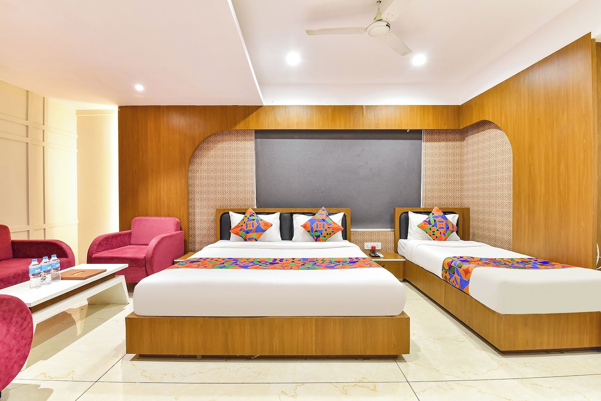 A hotel room with two beds, a desk, a chair, and a ceiling fan.