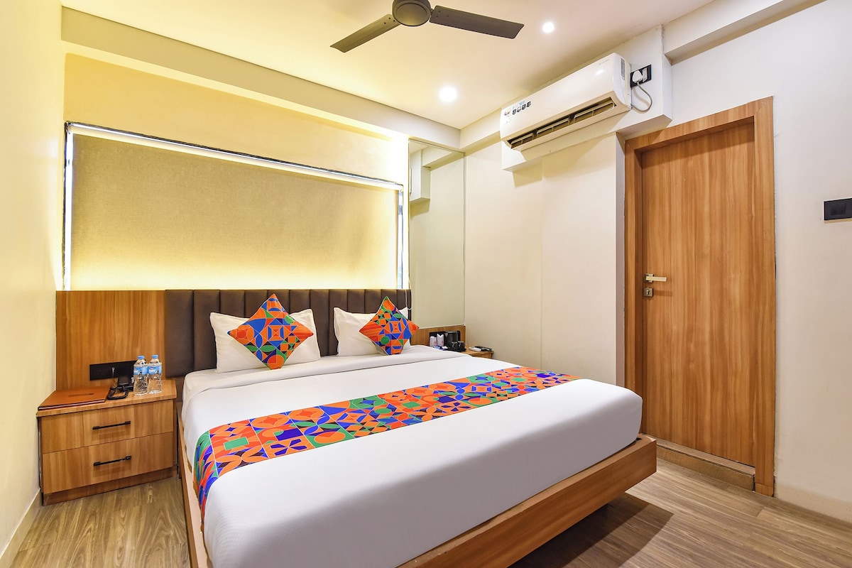 A hotel room with a bed, bedside tables, a nightstand, a ceiling fan, an air conditioning unit, and a wooden door.