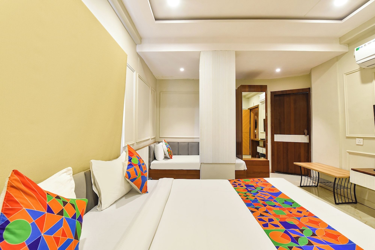 A hotel room with a bed, a desk, and a bathroom visible through an open door.
