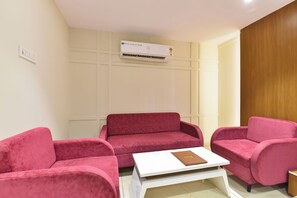 A room with a red sofa, a white coffee table, and a wooden panel wall. - FabHotel The Samsara (Ujjain)