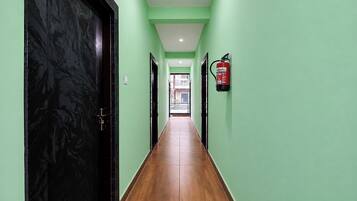 A hallway with green walls, a black door, and a fire extinguisher mounted on the wall.