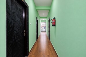 A hallway with green walls, a black door, and a fire extinguisher mounted on the wall.
