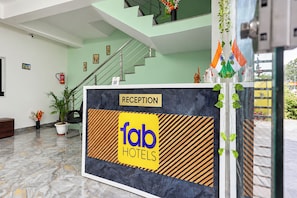A reception area with a reception desk labeled 'Tab Hotels,' a staircase, and indoor plants.