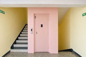 A pink door with a digital lock and a stairwell with a handrail. - FabHotel Apsara (Patna)