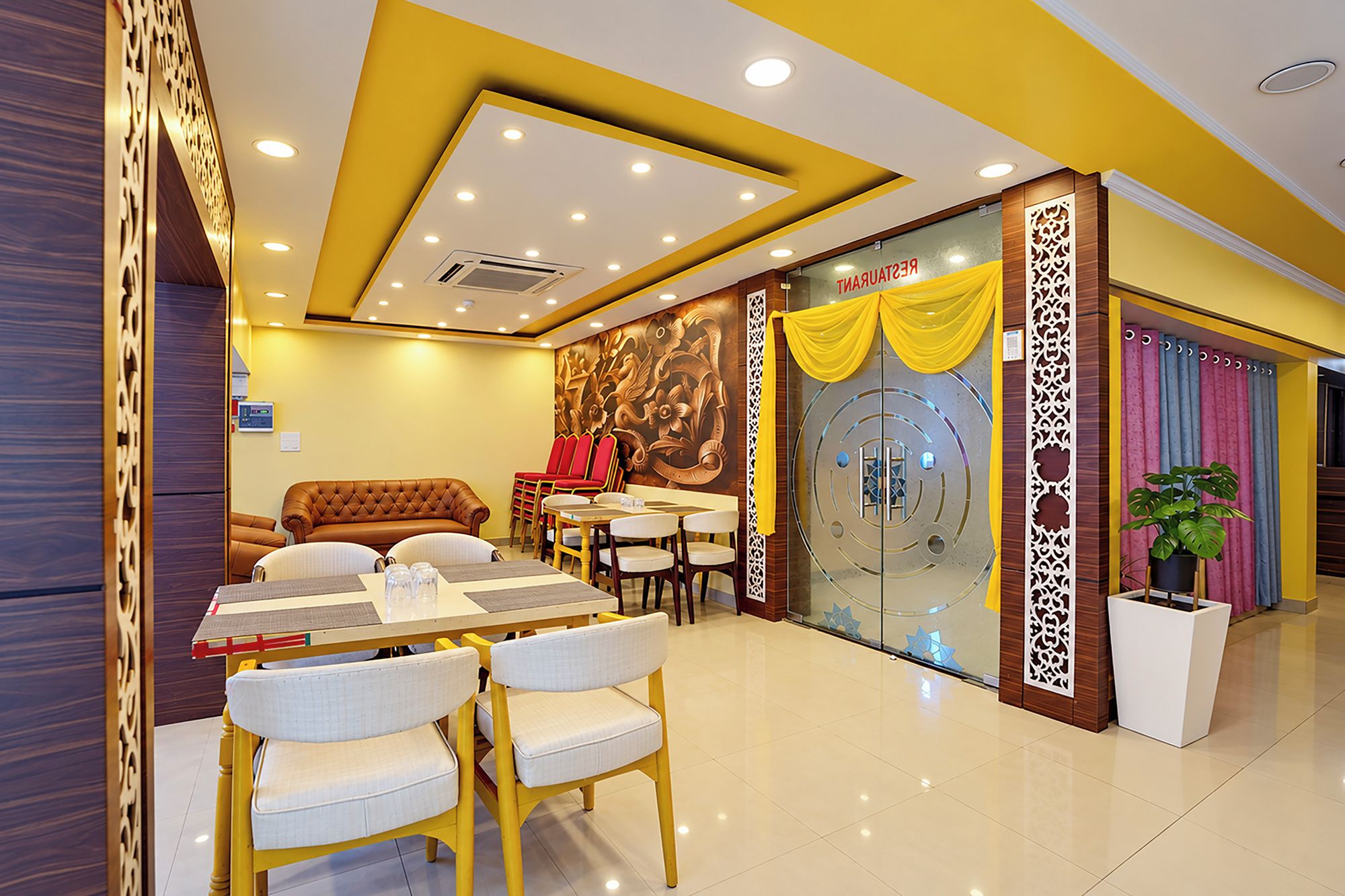Un restaurante con una decoración moderna, que incluye un comedor con mesas y sillas, un sofá y una pared decorativa con un mural floral.