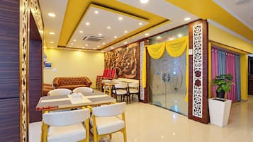 Un restaurante con una decoración moderna, que incluye un comedor con mesas y sillas, un sofá y una pared decorativa con un mural floral.
