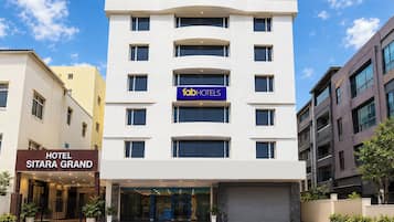 A modern hotel building with a sign for 'fabHOTELS' and 'HOTEL SITARA GRAND' visible.