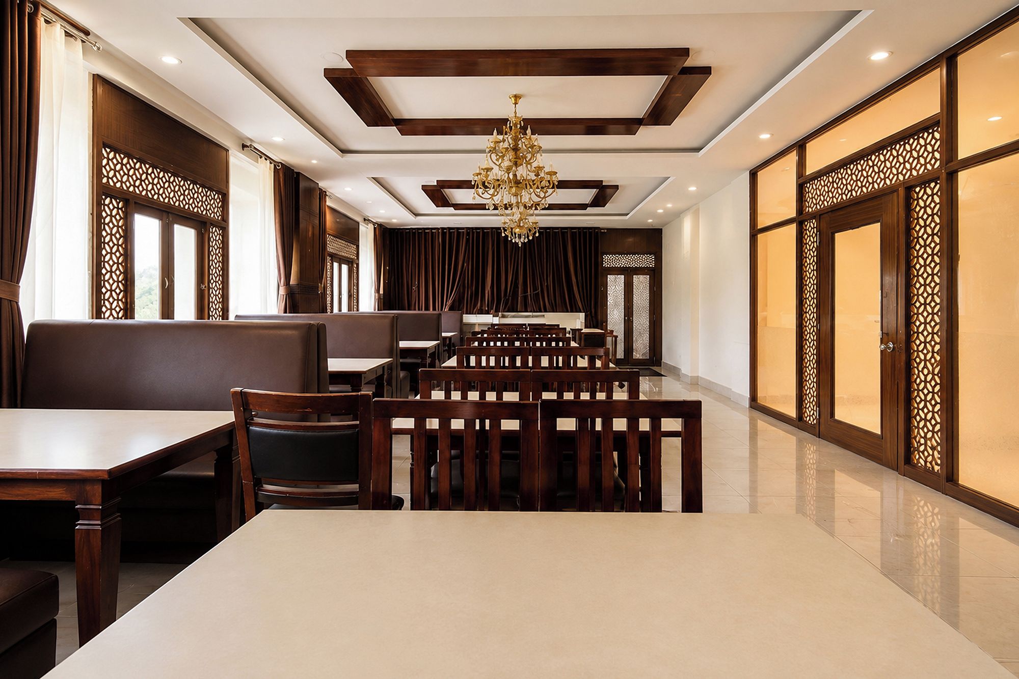 A restaurant with a long dining table, multiple booths, and a chandelier.