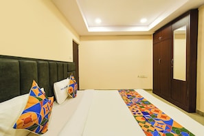 Una habitación de hotel con cama, almohadas, armario y espejo.