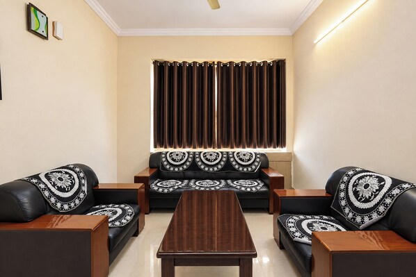 A living room with a sofa set, a coffee table, and a window with curtains.