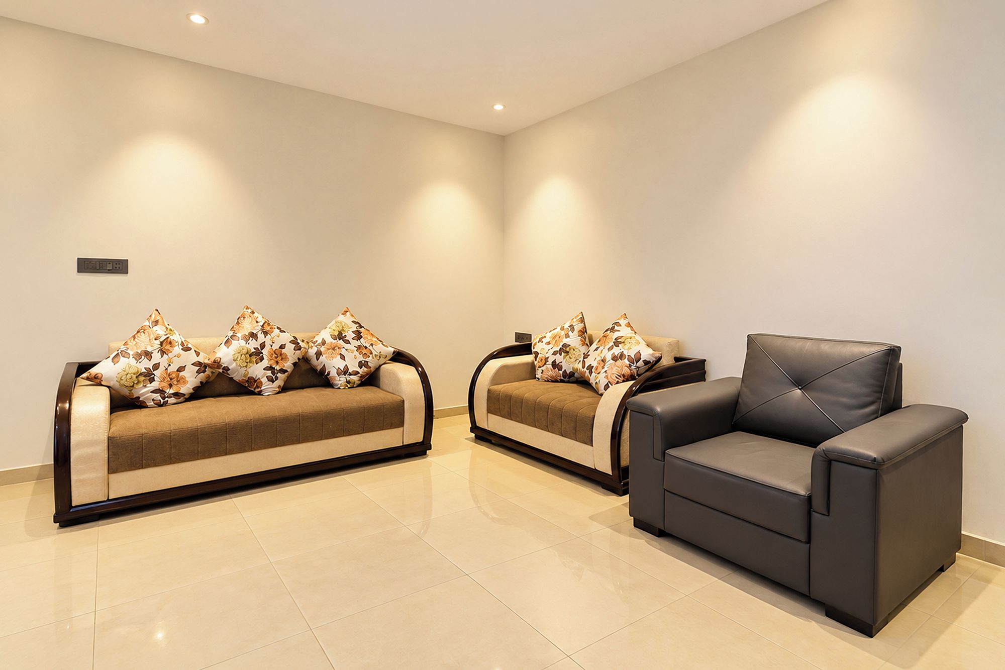 A modern living room with two sofas and a single armchair, all with dark upholstery.