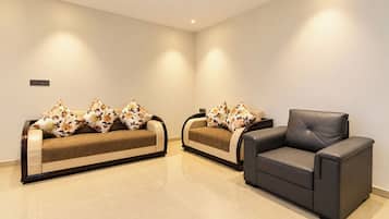 Una sala moderna con dos sofás y un sillón individual, todos con tapicería oscura.