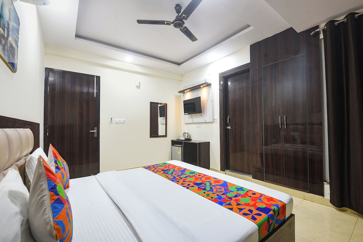 A hotel room with a bed, a ceiling fan, a TV, and wardrobes.