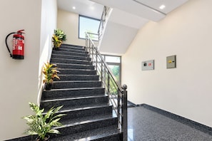 A staircase with a fire extinguisher mounted on the wall, potted plants, and emergency buttons. - FabHotel Swastik Anand Vihar (New Delhi)
