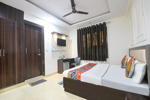 Une chambre d’hôtel équipée d’un lit, d’un bureau, d’une télévision et d’un ventilateur de plafond.
