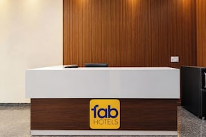 A reception desk with a wooden panel backdrop, a white counter, and a 'fab hotels' sign. - FabHotel Swastik Anand Vihar (New Delhi)