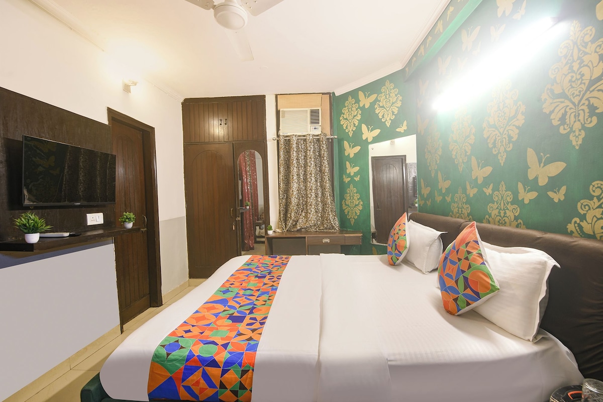 A hotel room with a bed, a television, a wardrobe, and a window with curtains.